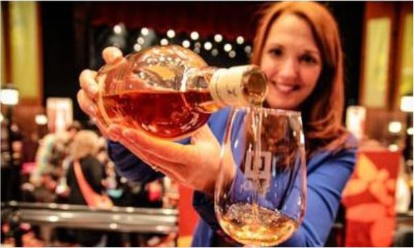 A woman pouring a glass of whisky at an event.