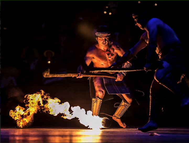 Two men are performing a fire dance in front of a crowd.