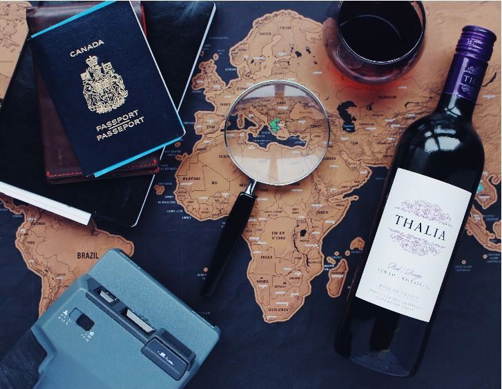 A bottle of wine, a passport and a magnifying glass on a map.
