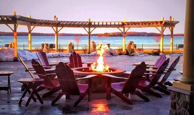 A fire pit in front of a gazebo overlooking the water.