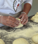 A chef is kneading dough for Pinsa Romana on a table.